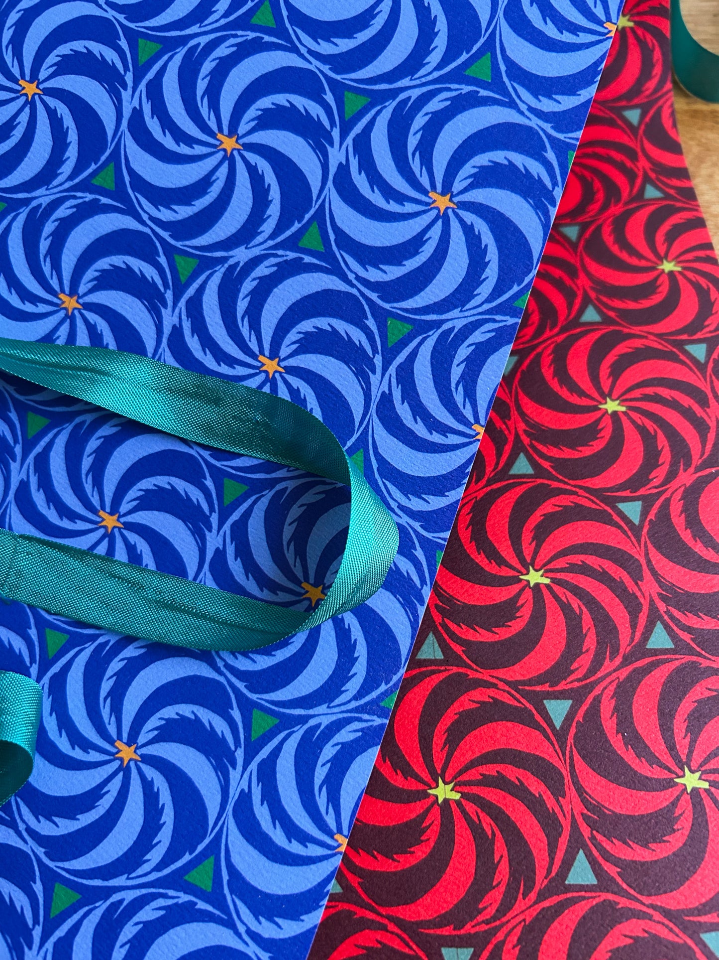close up of a double sided wrapping and crafting sheet with a blue pinwheel pattern on one side a red pinwheel pattern on the other