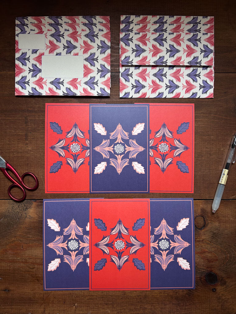 Set of patterned cards and matching patterned envelopes on a wooden surface with scissors and a ruler.