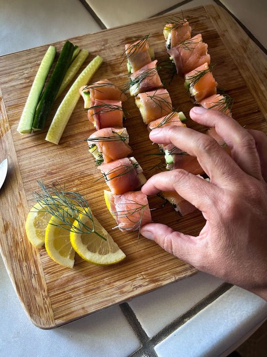 hand taking a salmon "sushi" roll from a serving tray