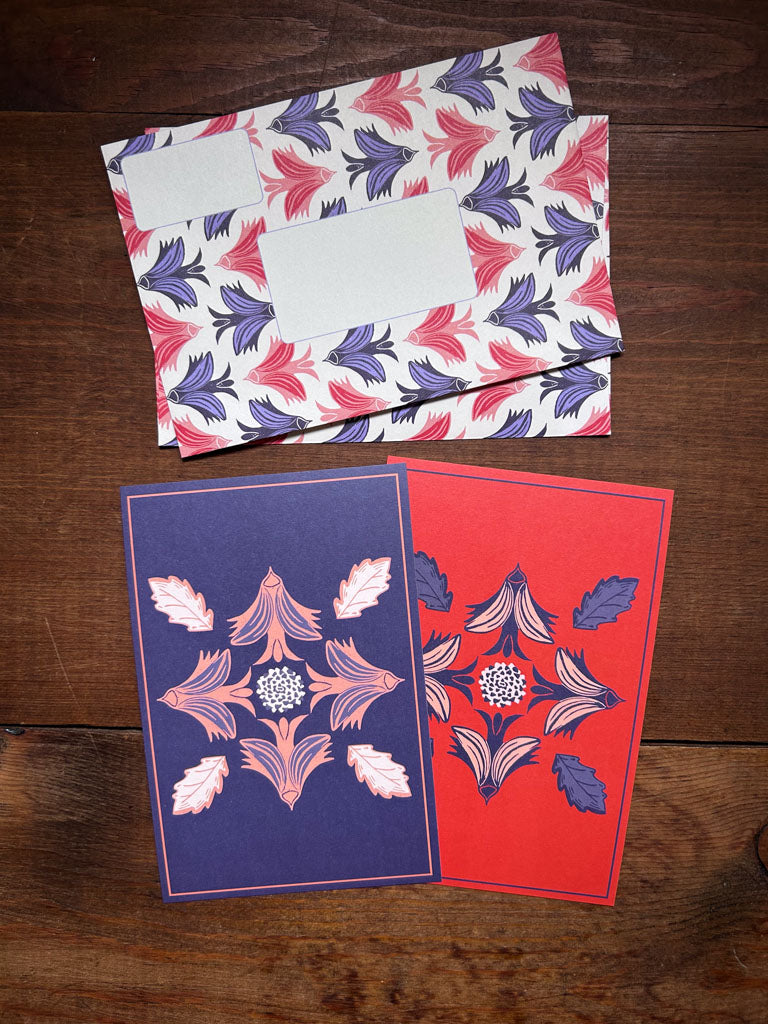 Two greeting cards with bird motifs and matching patterned envelopes on a wooden surface