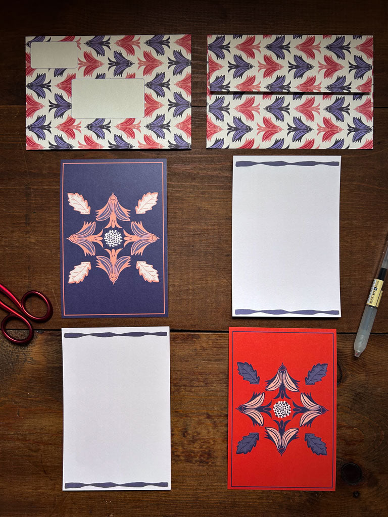 Set of stationery items with bird motifs and patterned envelopes on a wooden surface