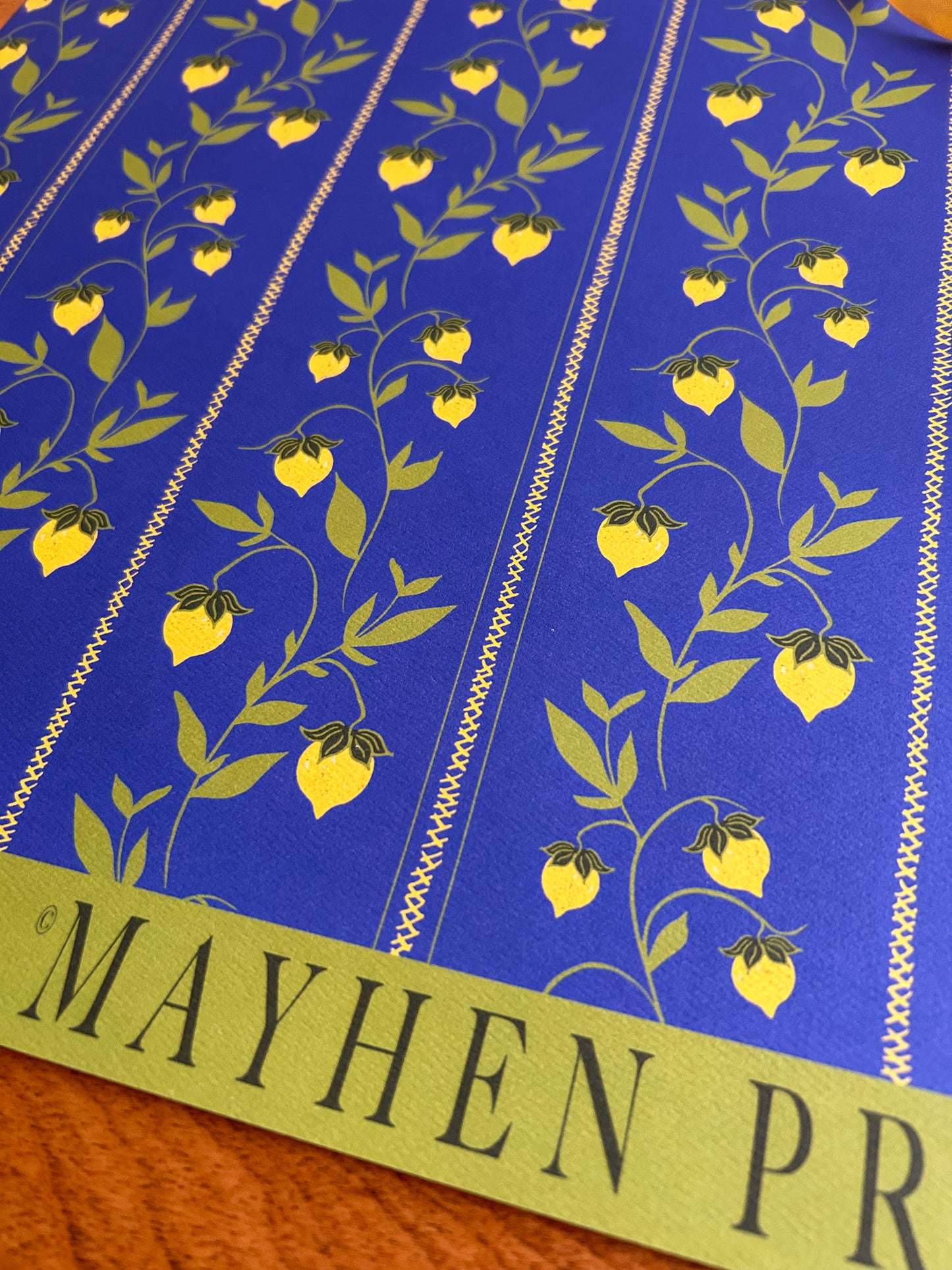 close up of a berry vine patterned wrapping sheet with yellow berries on a blue background