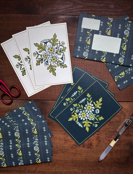 Floral stationery items including cards and patterned envelopes on a wooden surface.