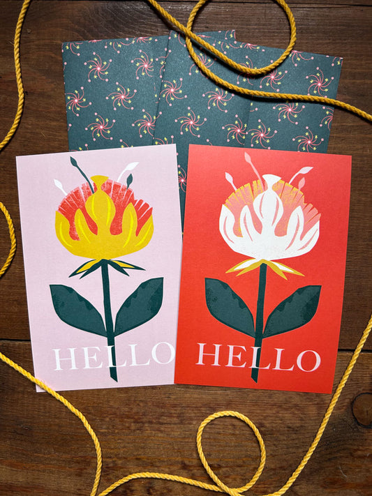 Colorful greeting cards with floral designs and 'HELLO' text with matching patterned envelopes on a wooden surface.
