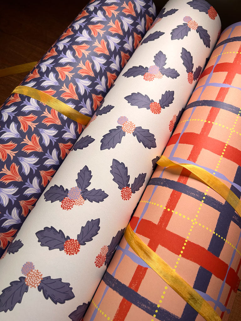 Three rolls of patterned fabric with linocut birds, plaid, and floral designs.