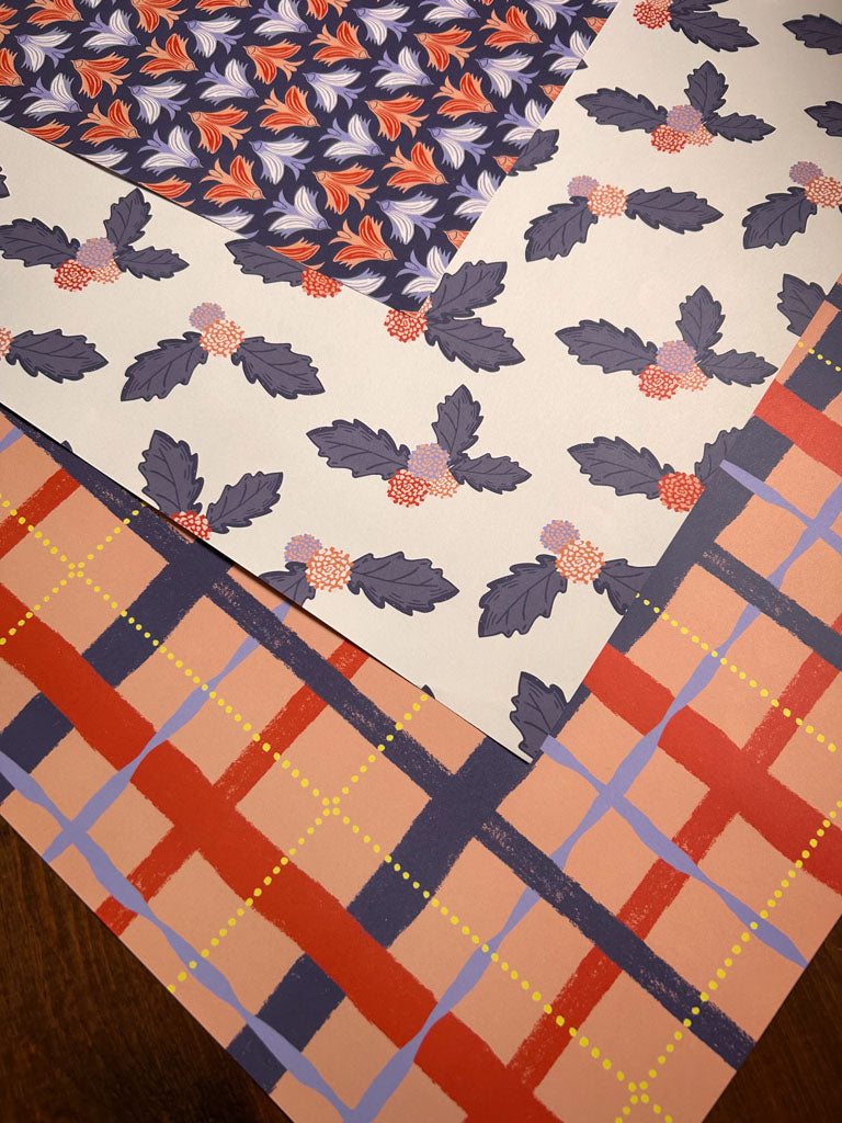 Three different patterned wrapping papers arranged on a wooden surface.