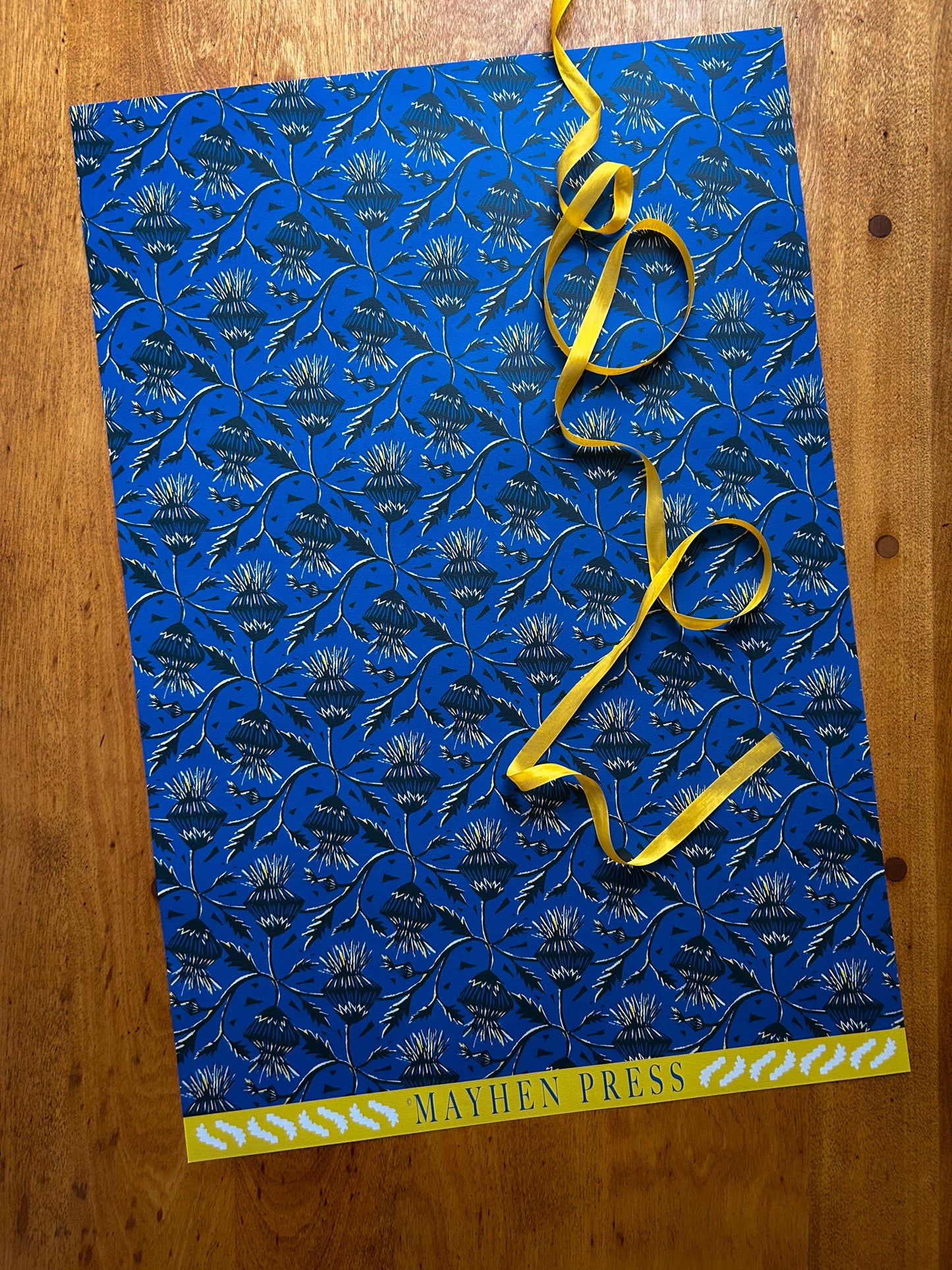 sheet of blue thistle flower patterned crafting paper  on a wooden background