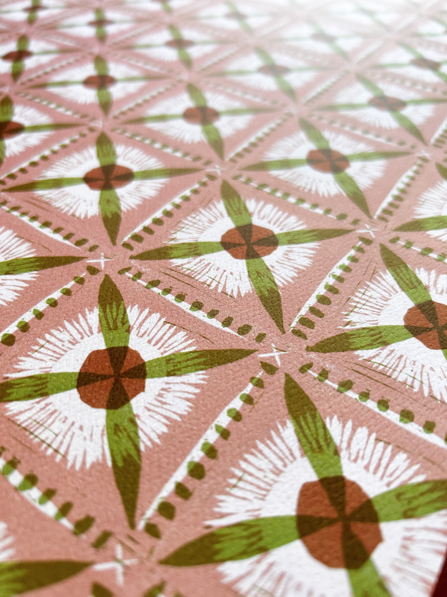 close up of dandelion cross patterned crafting paper with green on pink background