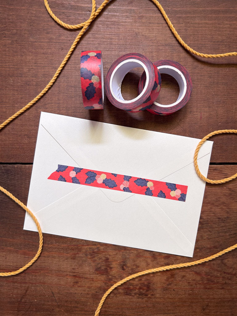Decorative tape with floral pattern on a white envelope against a wooden background