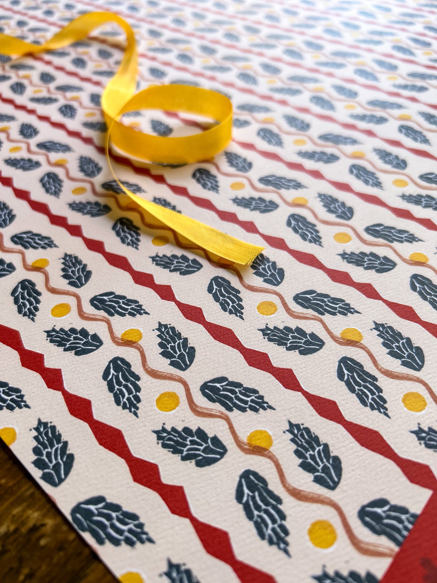 close up of a pinecone panel patterned wrapping and crafting paper sheet with blue pinecones on a cream background