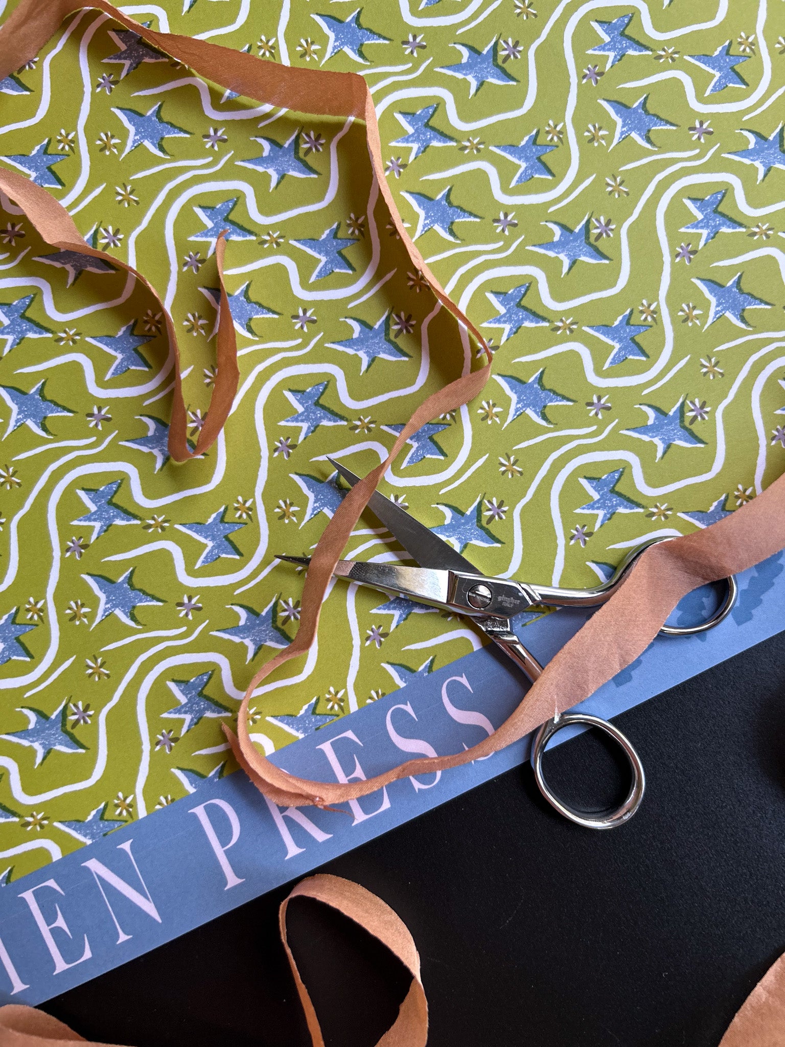 close up of a shooting star patterned crafting paper sheet with blue stars on a green background