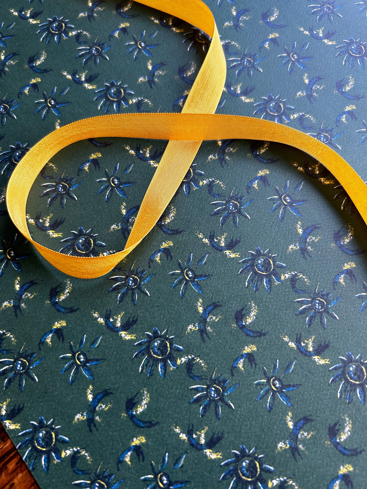 close up of daisy floral patterned wrapping paper with blue flowers on a rich green background