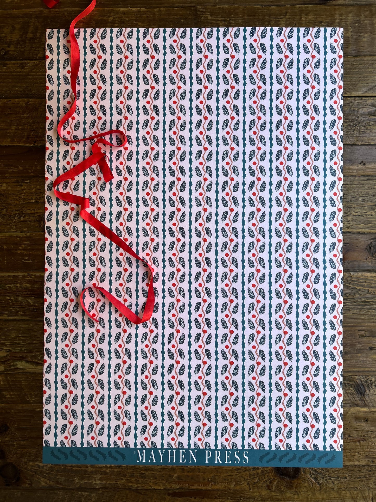 full sheet of pinecone patterned crafting paper on a wooden background featuring 'Mayhen Press' branding