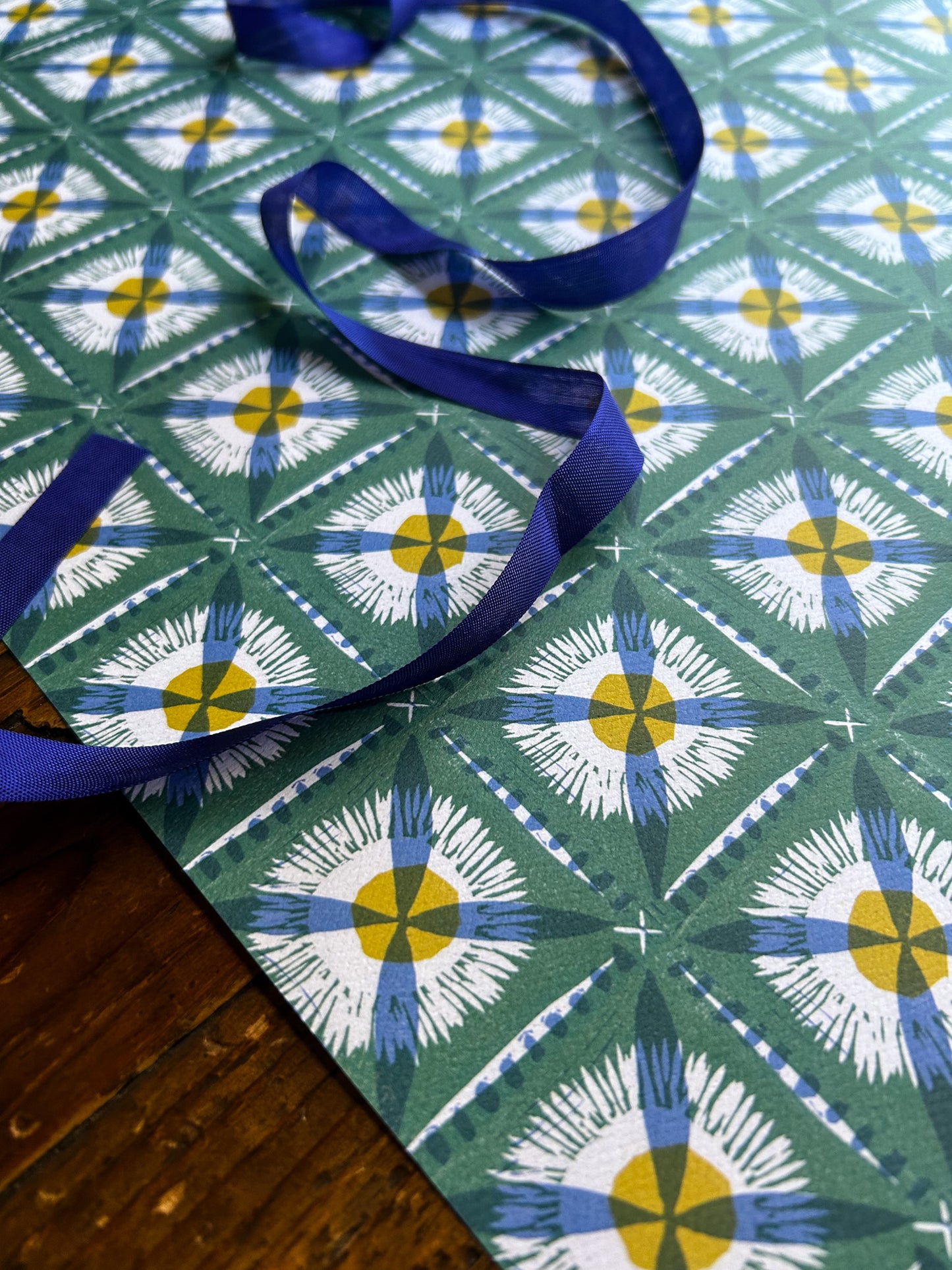 close up of dandelion cross patterned crafting paper with blue on green background